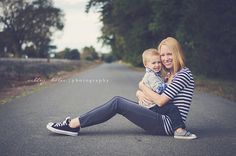 a woman sitting on the side of a road holding a small child in her arms