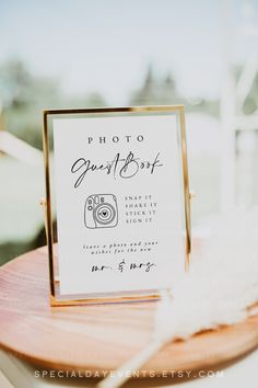 a photo guest sign on top of a wooden table next to a white and gold plate