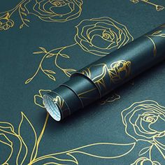 a pen sitting on top of a green surface with gold foil flowers and leaves around it