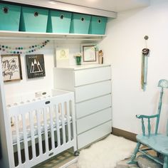 a baby's room with a white crib, blue rocking chair and dresser