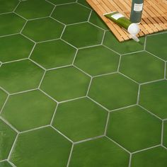 a green tile floor next to a wooden deck with a bottle of wine on it