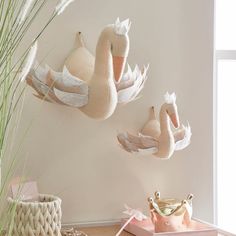 three swans are hanging on the wall next to a potted plant and other items