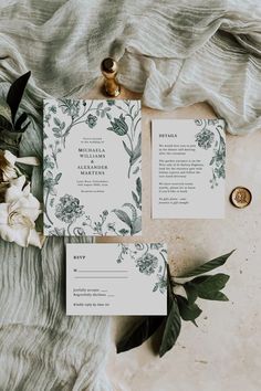 the wedding stationery is laid out with flowers and greenery