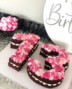 a chocolate cake with pink frosting and the number 50 spelled out in front of it