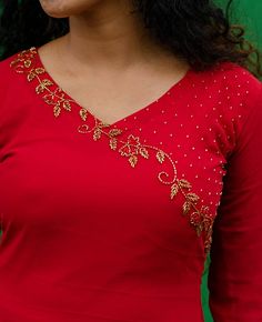 a woman wearing a red top with gold embellishments on her chest and shoulders