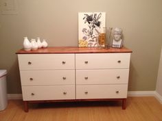 a white dresser with two vases sitting on top of it next to a painting