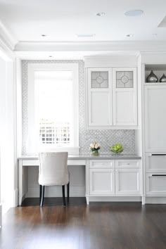 a white kitchen with wood floors and cabinets in the corner, along with a dining room table