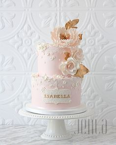 a pink and gold wedding cake with flowers on top