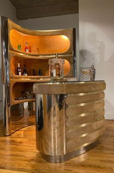 an unusual bar in the middle of a room with wood floors and stainless steel fixtures