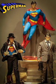 two action figures are posed in front of a superman figure and another one is wearing a suit