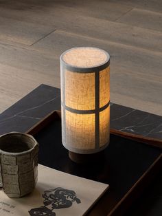 a table topped with a cup next to a lamp on top of a wooden tray