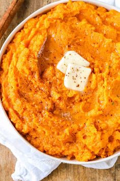 a white bowl filled with mashed sweet potatoes and topped with a pate of butter