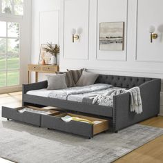 a daybed with drawers underneath it in a room next to a rug and table