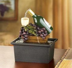 a bottle of wine being poured into a container with grapes in it on a desk