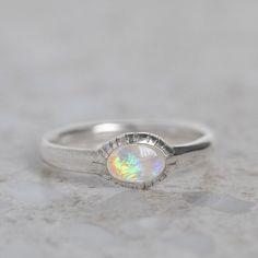 Our ancient inspired Parthian stacking ring is set with an oval crystal opal from Coober Pedy. Opal measures 6 x 4mm. Approx band width 2.6mm - 1.7mm at back of band. Approx weight: 2.3g in silver, 2.5g in 9ct gold. Pictured in first image with a matte finish. For a high shine finish please leave a note at checkout. Please note, we will match the opal as close to the image as possible. Each opal is unique and may vary in appearance and colour from what is depicted on the site. Spiritual Oval Opal Birthstone Ring, Oval Opal Stackable Rings As Gift, Spiritual Oval Opal Promise Ring, Spiritual Oval Opal Ring, Stackable Oval Opal Rings, Adjustable Stackable Oval Opal Ring, Oval Opal Stackable Rings, Opal Stacking Ring, Coober Pedy