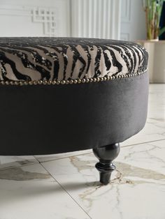 a zebra print ottoman sitting on top of a white floor next to a potted plant