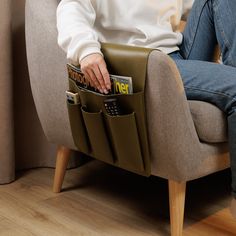 a person sitting in a chair holding a cell phone and magazine holder on their lap