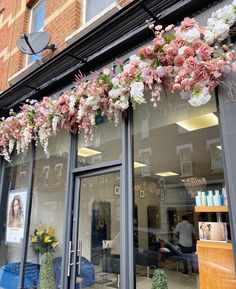 a store front with flowers hanging from the windows