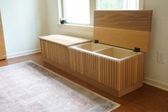 a wooden bench sitting next to a window on top of a hard wood floor in front of a rug