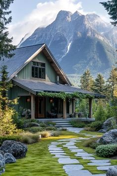 a house in the mountains with green grass and stepping stones leading up to it's front door