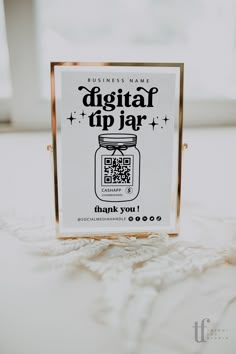 a business card sitting on top of a white tablecloth next to a glass container with qr code printed on it