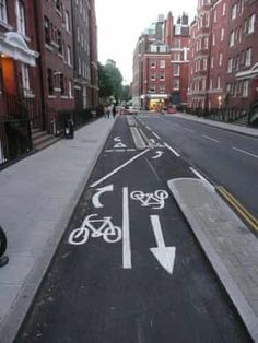 a bike lane painted on the side of a city street with buildings in the background