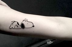 a person's arm with a small snoopy tattoo on it