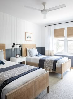 two beds in a bedroom with white walls and wood trim on the headboard,