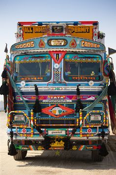 an elaborately decorated bus is parked on the side of the road in front of another vehicle