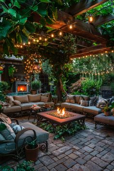 an outdoor living area with couches, tables and fire pit surrounded by greenery