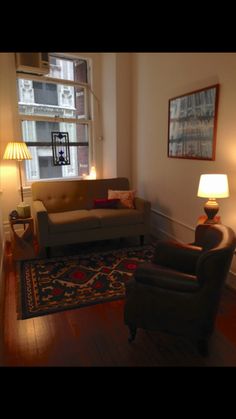 a living room with a couch, chair and rug in front of a large window