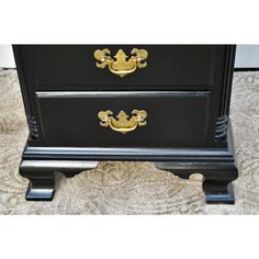 a black dresser with gold handles on it's sides and two drawers in the middle