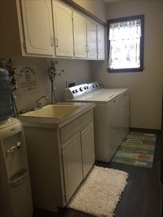 a washer and dryer sitting in a kitchen next to a window with a rug on the floor