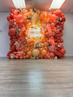 an orange and white balloon wall with a buddha statue surrounded by balloons in the center