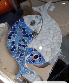 a blue and white fish made out of sea glass mosaics on a counter top