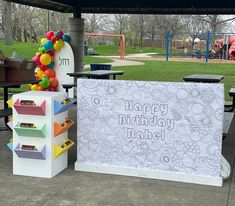 an outdoor birthday party setup with balloons and decorations on the table, including a sign that says happy birthday rachel