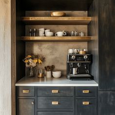 the coffee maker is sitting on top of the counter in the kitchen, and it's built - in shelves are filled with dishes