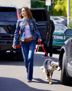 a woman walking her dog down the street