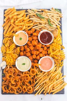 a platter filled with different types of food and dipping sauces on top of it