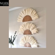 three decorative wall hangings with white and brown fan shaped designs on the wall above them