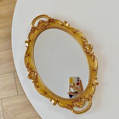 a mirror sitting on top of a white table next to a wooden floor and wall