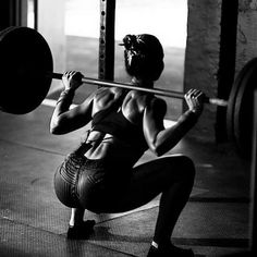 a woman squats while holding a barbell