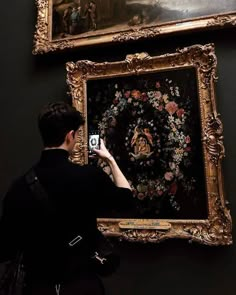 a man taking a photo of a painting on display