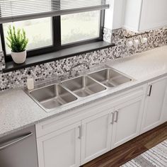 a kitchen with white cabinets and granite counter tops is shown in this image, there are two plants on the window sill