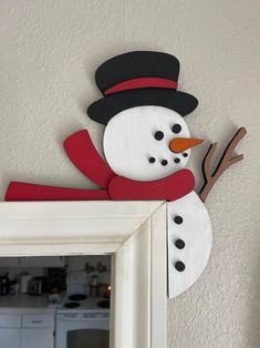 a snowman is hanging on the wall next to a mirror