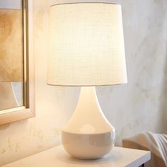 a white lamp sitting on top of a table next to a mirror