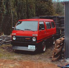 a red van parked next to a pile of wood