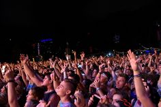 a large group of people at a concert with their hands in the air and one person holding up his cell phone