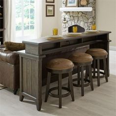 a kitchen table with four stools in front of it and a stone fireplace behind it