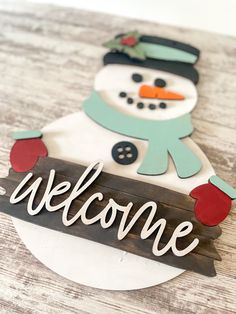 a wooden sign that says welcome with a snowman on it